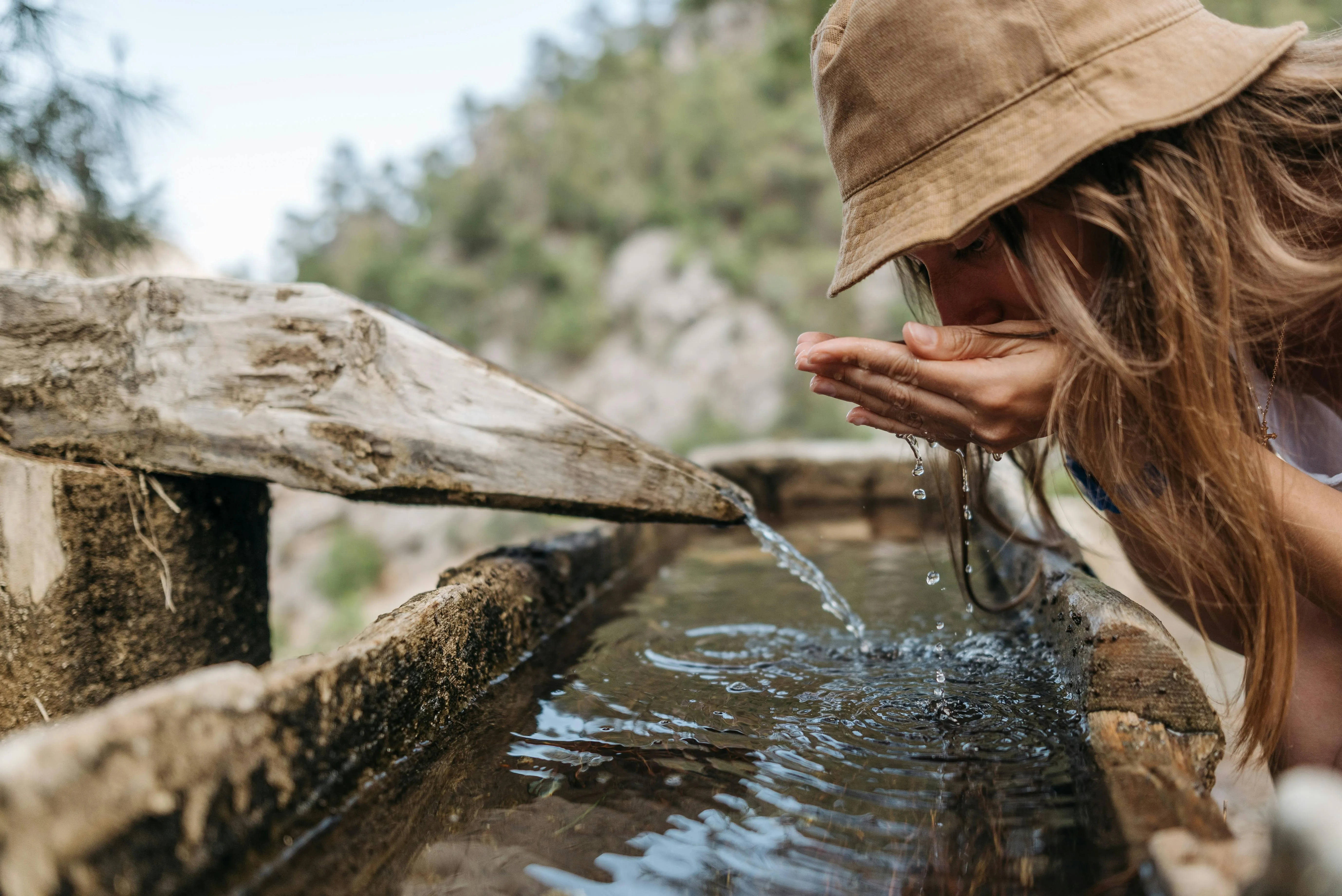 persona bebiendo agua de una fuente
